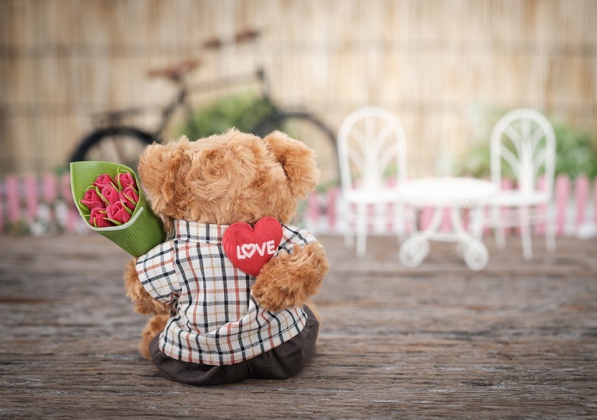 Ini adalah gambar boneka beruang yang memegang bunga mawar